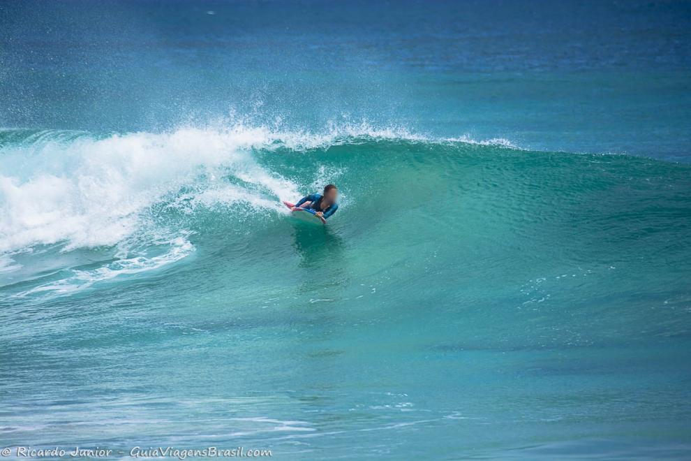 Imagem de uma menina surfando nas onda de Noronha.